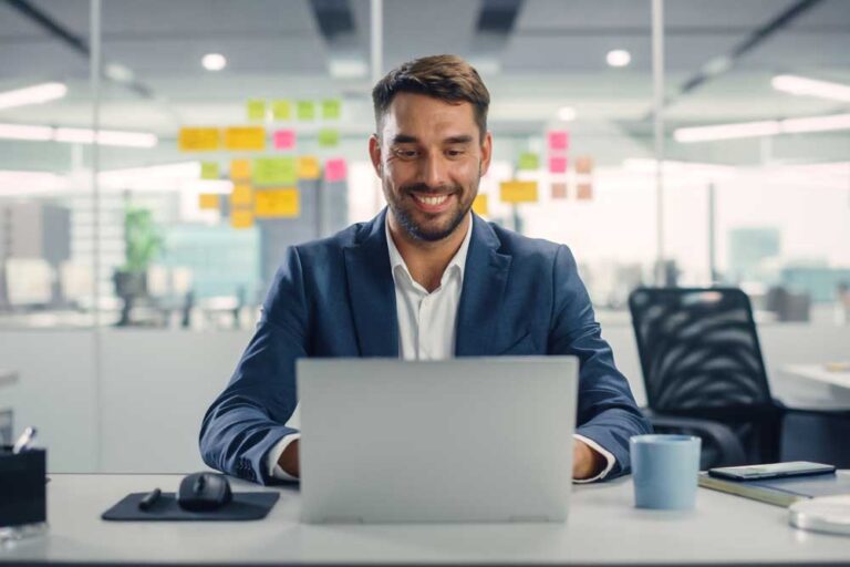 hombre sonriendo mirando la pantalla de su computador