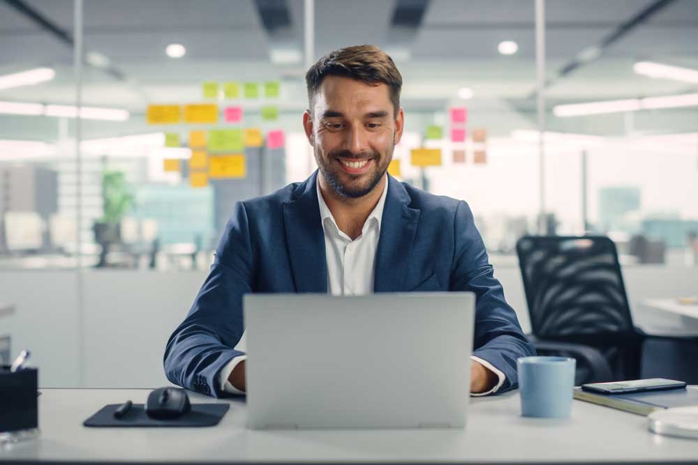 hombre sonriendo mirando la pantalla de su computador